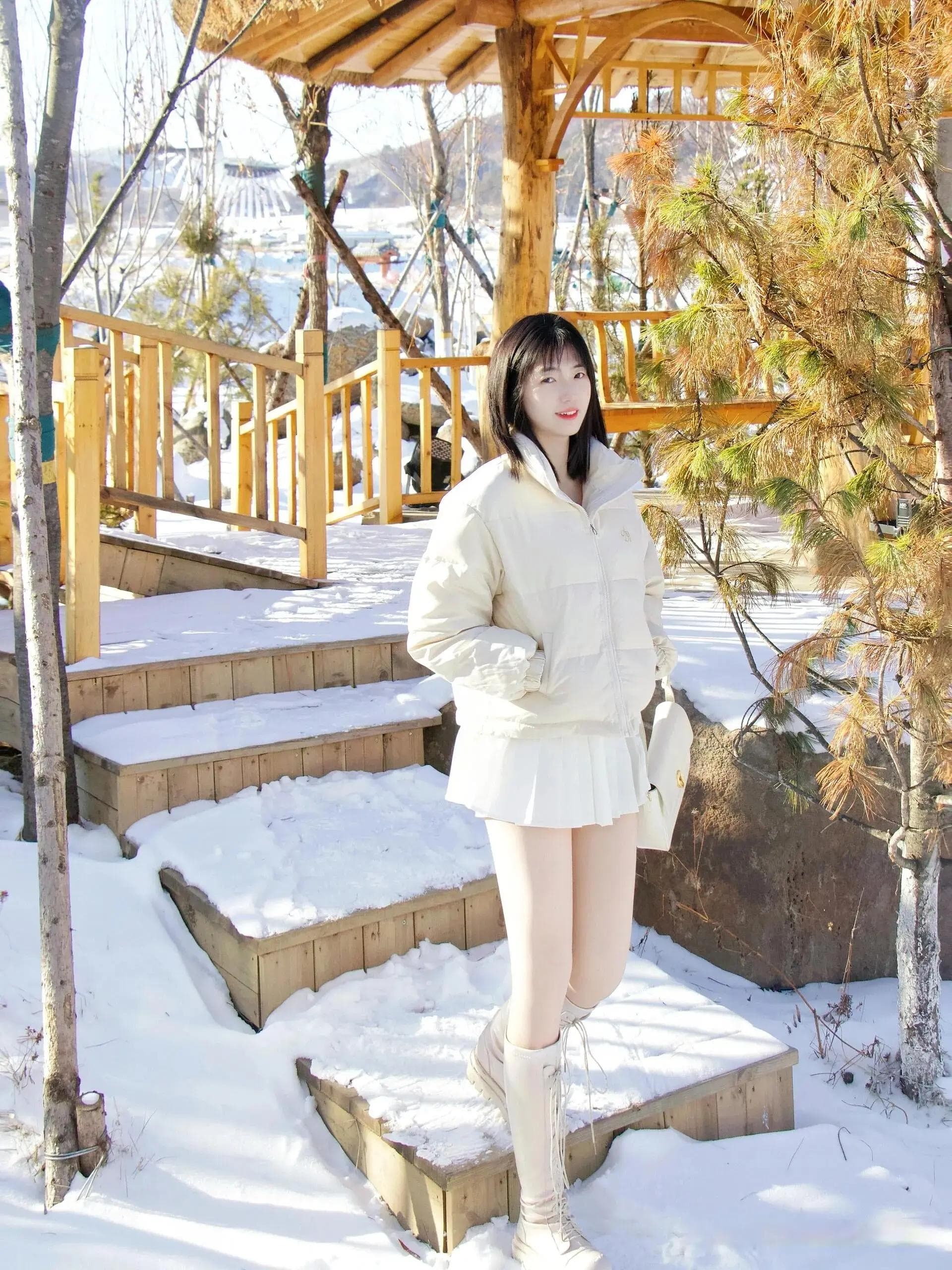 冬日暖阳：白色羽绒服女子雪地里摄影